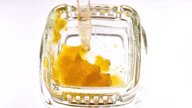 Macro view of marijuana concentrate wax in a small glass container.  