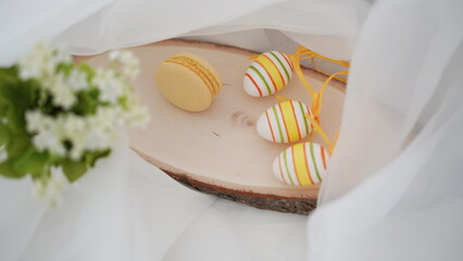 Easter setup - eggs and yellow french macarons on white background
