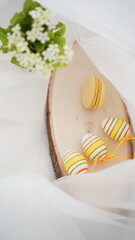 Easter setup - eggs and yellow french macarons on white background 
