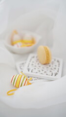 Easter setup - eggs and yellow french macarons on white background

