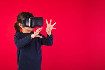 Side view of little girl wearing virtual reality goggles amazed and touching with her hands...