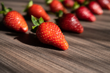 Wooden background for text with red, fresh and ripe strawberries. Summer decoration from berries. High quality photo