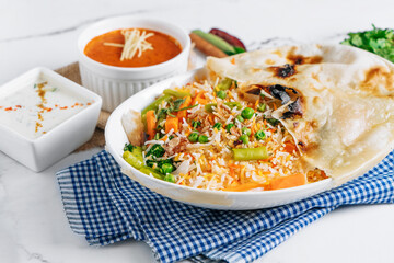 vegetable biryani with raita and sauce in a dish isolated on napkin side view on grey background famous indian and pakistani food