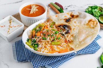 vegetable biryani with raita and sauce in a dish isolated on napkin side view on grey background famous indian and pakistani food