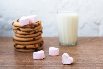 Fragrant, tasty, homemade cookies with raisins, marshmallows in the form of hearts and a glass of fresh milk on the table. Delicious, hearty, healthy breakfast. Copy space, high resolution