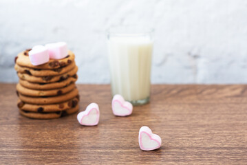 Fragrant, tasty, homemade cookies with raisins, marshmallows in the form of hearts and glass of fresh milk on the table