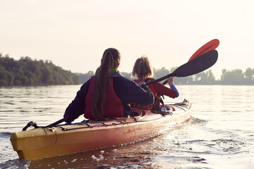 Two active women, best friends kayaking in a river at autumn season. Kayaking, travel, leisure...