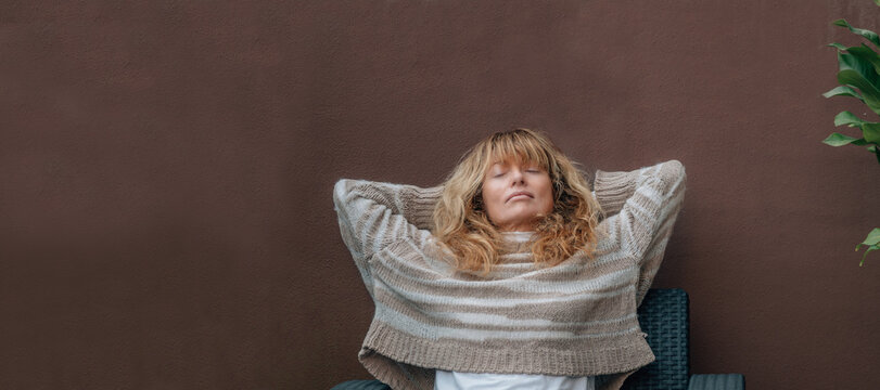 middle-aged woman resting relaxed on the terrace sofa