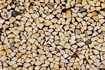 Stacked chopped wood close-up texture. Firewood storage background. Stocks of wooden logs. Chopping wood for a fireplace. Woodpile with firewood with visible wooden texture.