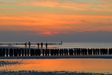 Menschen sind im Abendrot am Strand der Nordsee