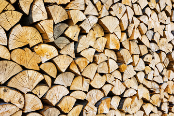 Fototapeta premium Stacked chopped wood close-up texture. Firewood storage background. Stocks of wooden logs. Chopping wood for a fireplace. Woodpile with firewood with visible wooden texture.