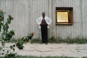 Stylish african man model looking away wearing white shirt on country side over wooden wall background