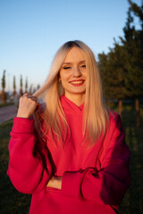 Happy smiling blonde girl in a pink fleece tracksuit has a good time outdoors. The joy of active recreation. High quality photo