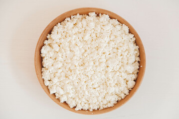 Cottage cheese in a wooden bowl on a white background