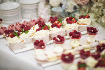 Delicious dessert of cake with fresh strawberries, raspberries and mint leaf. Banquet table full of fruits and berries and an assortment of sweets. Candy bar.