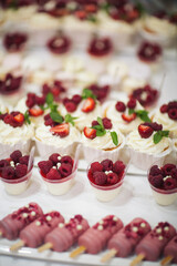 Delicious dessert of cake with fresh strawberries, raspberries and mint leaf. Banquet table full of fruits and berries and an assortment of sweets. Candy bar.