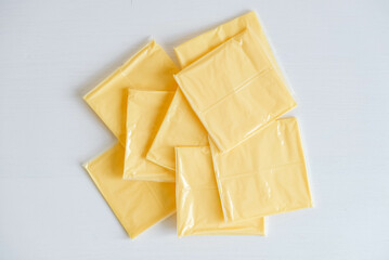 Separately packed cheese slices on a white wooden table background