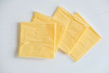 Separately packed cheese slices on a white wooden table background