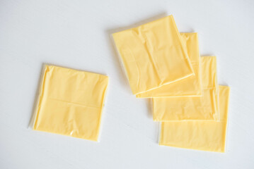 Separately packed cheese slices on a white wooden table background