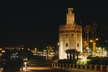Fototapeta na wymiar La Torre de Oro in Seville, Spain at night brightly lit on by the river