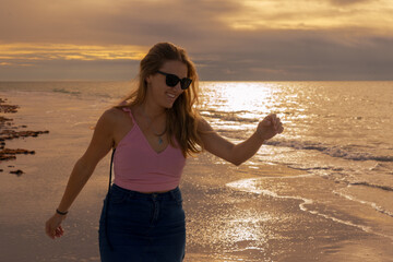 Young blonde woman enjoying on the beach at sunset