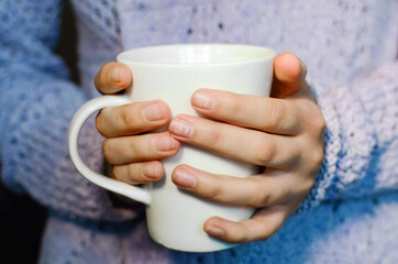 White Cup of tea in the hands of a girl, close-up. Lifestyle concept.