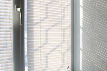 The light passes through the plastic blinds on the window, close-up.