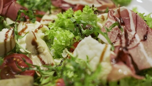 Appetizing Salad On Plate. It Consists Of Cheese Olives Meat Salad Leaves Meat. Sauce Is Poured On Salad.