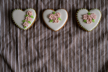 White gingerbread cookies with icing and flower decoration on a striped towel. Background for International Women's Day or Valentine's Day. High quality photo