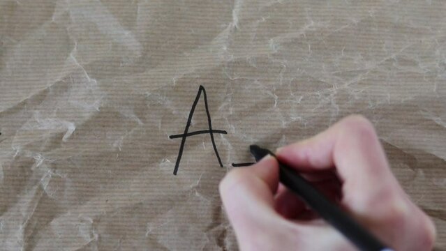 Human handwriting Greek letters alpha and omega on a crumpled paper with black marker.
