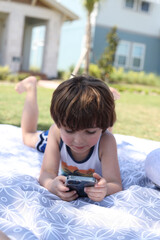 Little boy in the park on a blanket in front of a neighborhood of Laureate Park at Lake Nona having a picnic 