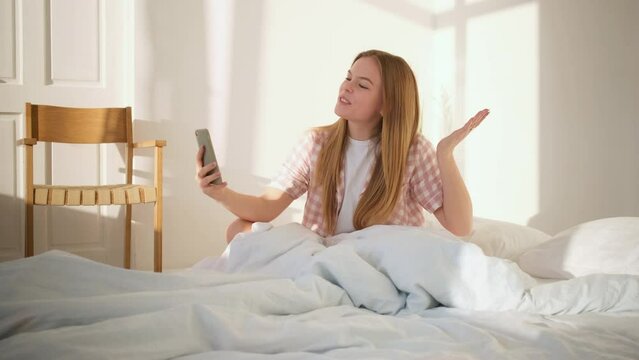 Woman talking on video call in bed
