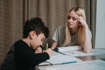 Mom and son are doing homework. Sister helps brother solve math. Home schooling. High quality photo