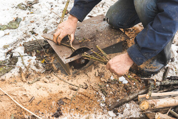 Man cutting wood using stationary circular saw outdoors in winter for kindling close-up view