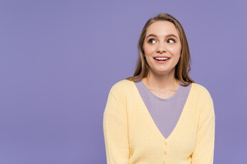 Obraz premium smiling and young woman looking away isolated on purple.