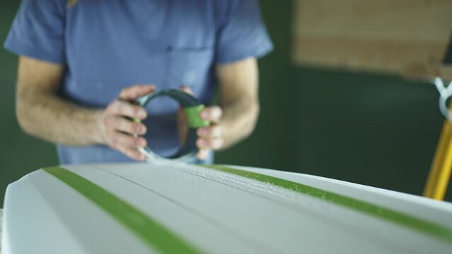 Surfboard making, shaper sands surfboard with sanding block. Concept of craftsmanship, small business in America, skilled professional in USA. Surfing industry. 