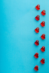 Frame for Valentine's Day hearts made of red glass pebbles on a blue background.