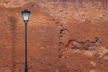 Metal black street lamp on a background of a red brick wall ...