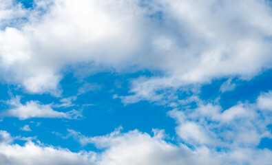 Fluffy white clouds against a blue sky on a warm sunny day. Gentle and slowly floating clouds as a concept of a quiet life.