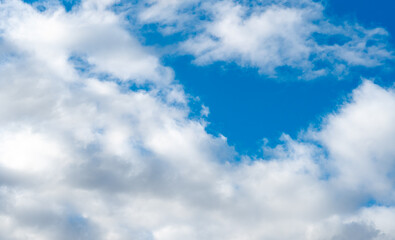 Fluffy white clouds against a blue sky on a warm sunny day. Gentle and slowly floating clouds as a concept of a quiet life.