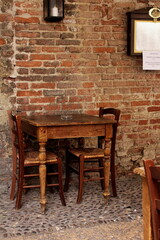 A wooden table and two chairs against the background of an old brick wall, Italy