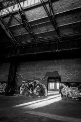 Dortmund, GERMANY - 19. March 2022: on the former Phoenix West industrial site, the rising sun shines through an old passageway in a brick-walled hall. The walls are sprayed with graffiti.