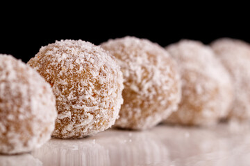 Beautiful sweets with coconut on a white plate on a black background
