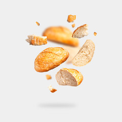 Classic white wheat bread flying on gray background. Round whole and pieces crispy fresh bread, healthy organic food, traditional pastries, bakery. Creative food concept for advertising, design