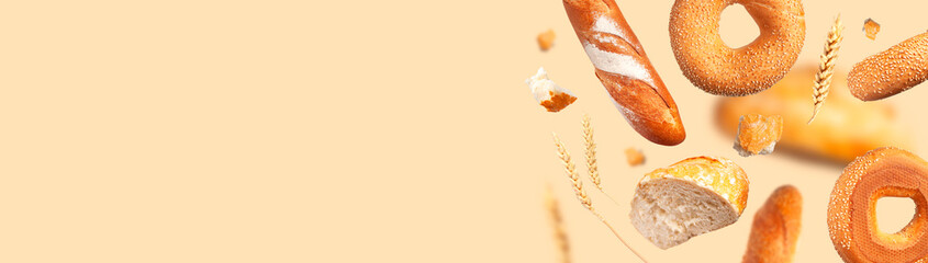 Creative food concept. Various types of bread, ears of wheat flying on beige background. Classic wheat round bread, baguette, bun, sesame bagel. Organic Healthy Fresh bread for bakery advertising