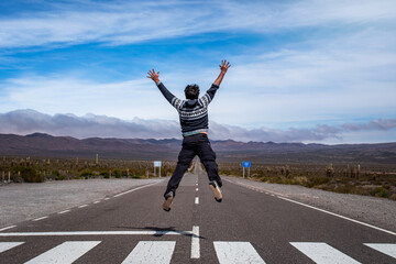 Turista saltando en la recta del Tintin, en el Parque Nacional los Cardones, Cachi, Salta