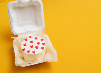 Bento cake in the form of circle with small red hearts in eco packaging. Picture for websites about...