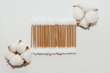 Eco-friendly bamboo cosmetic cotton buds with cotton on a light background.