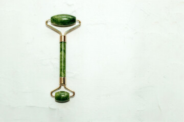 massage stone jade gouache scraper and facial roller light background. © ir1ska
