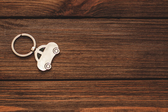 The keychain with a picture of a car in the shape of a house on a wooden background.